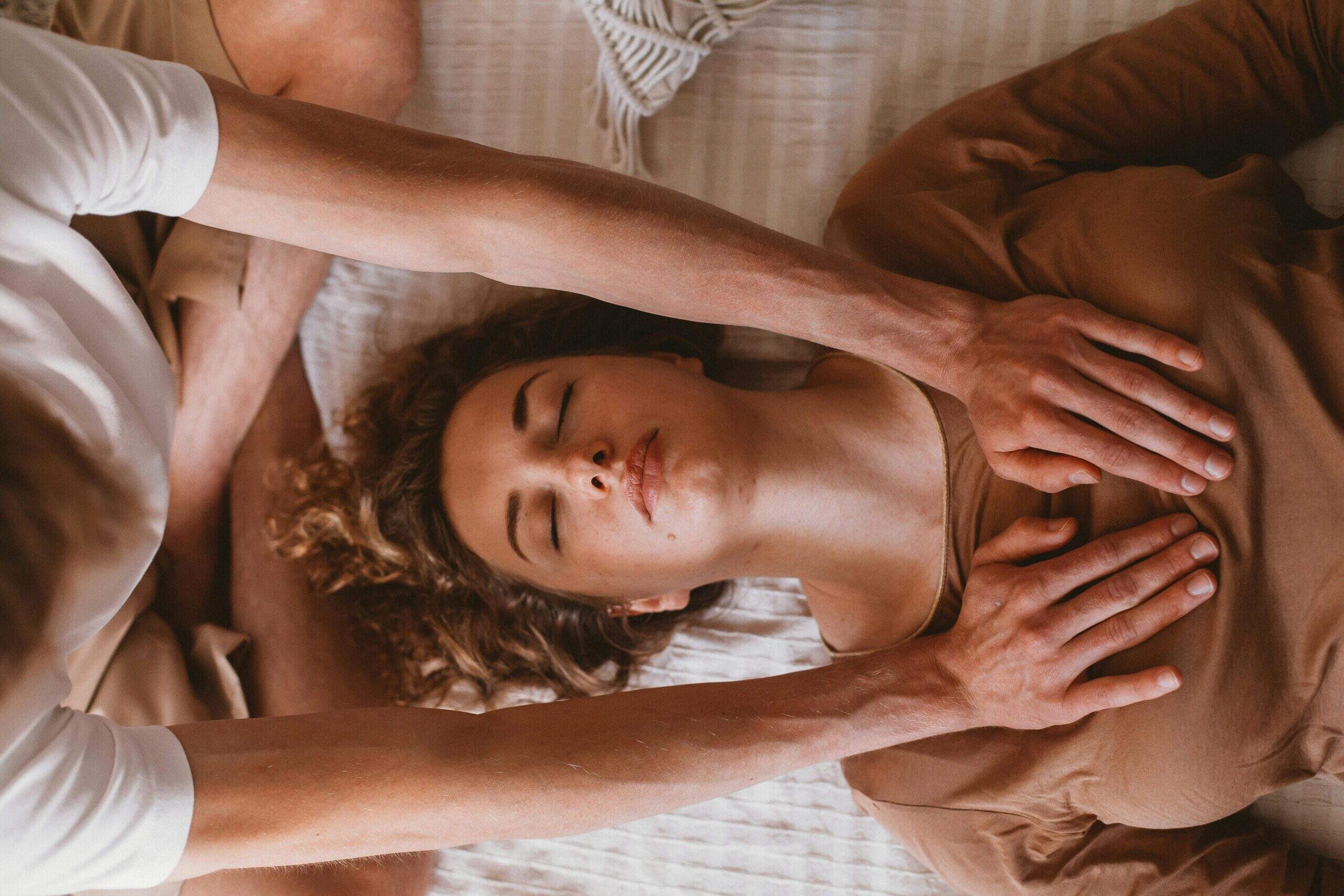 Praticien réalisant un soin énergétique en posant ses mains sur la poitrine d’une femme allongée