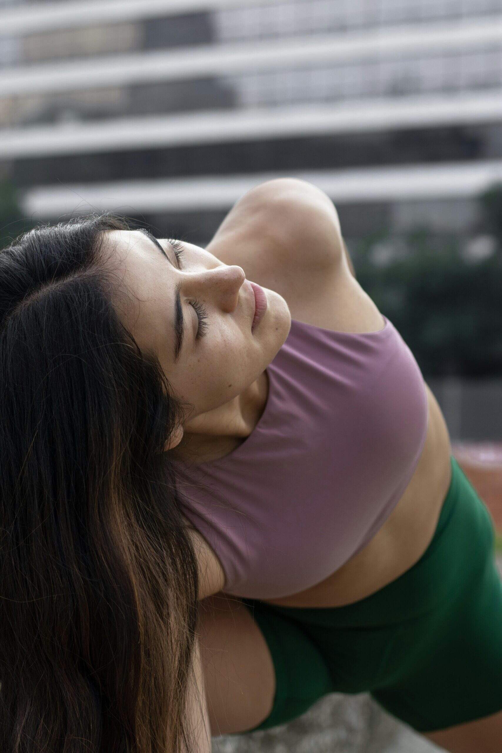 Femme concentrée en pleine posture de yoga sur une terrasse urbaine, les yeux fermés, en quête d’équilibre.