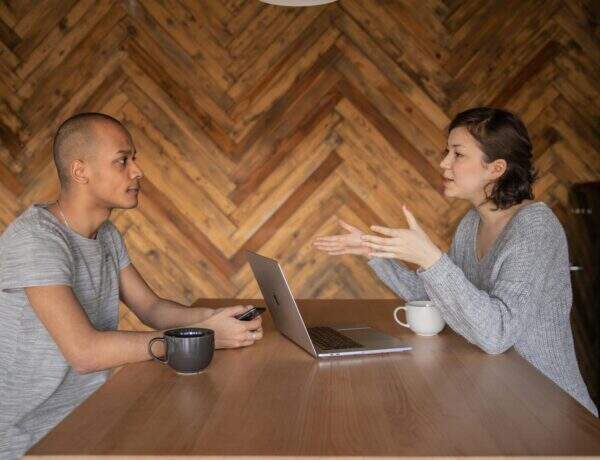 Deux personnes discutant face à face autour d'une table avec un ordinateur