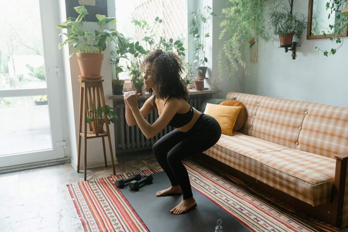 Femme faisant des squats dans son salon