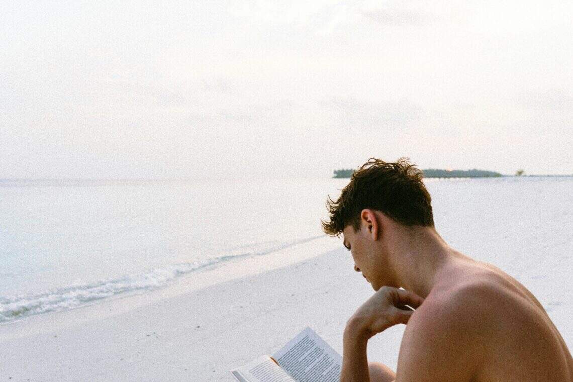 Homme lisant un livre sur la plage