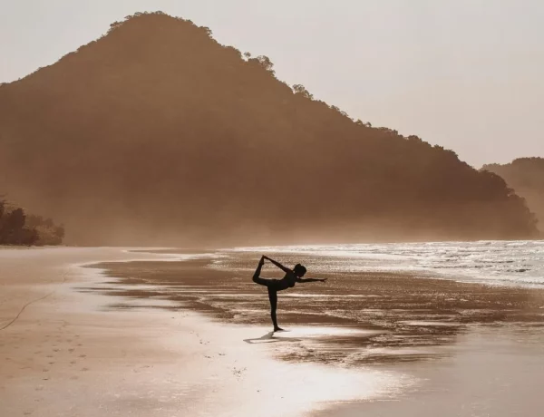 Personne faisant du yoga sur une plage paradisiaque.