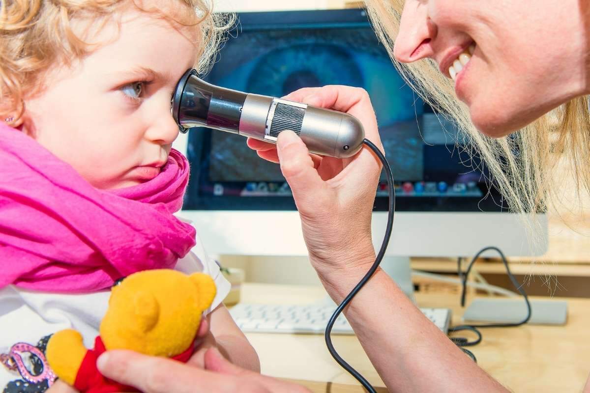 Iridologue en observation de l'iris d'un enfant durant une séance en iridologie.