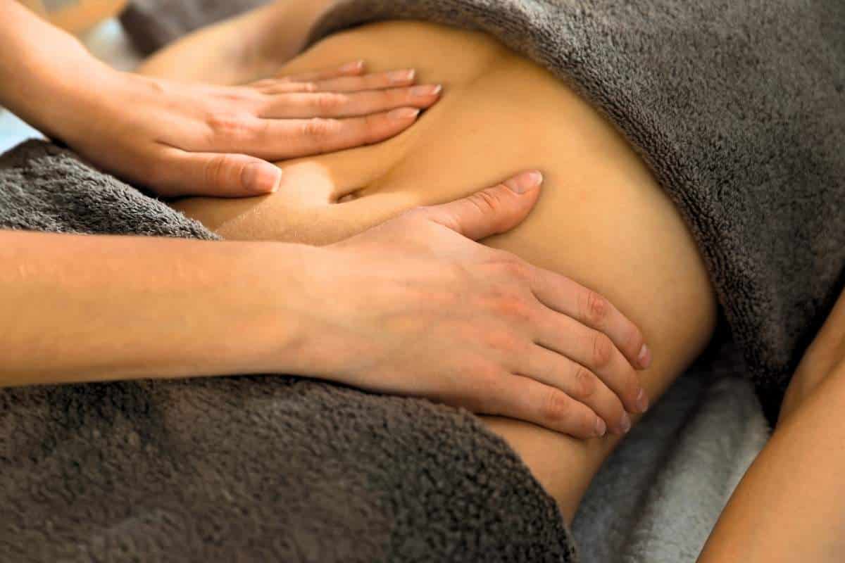 Praticien en drainage lymphatique entrain de manipuler durant une séance avec une cliente.