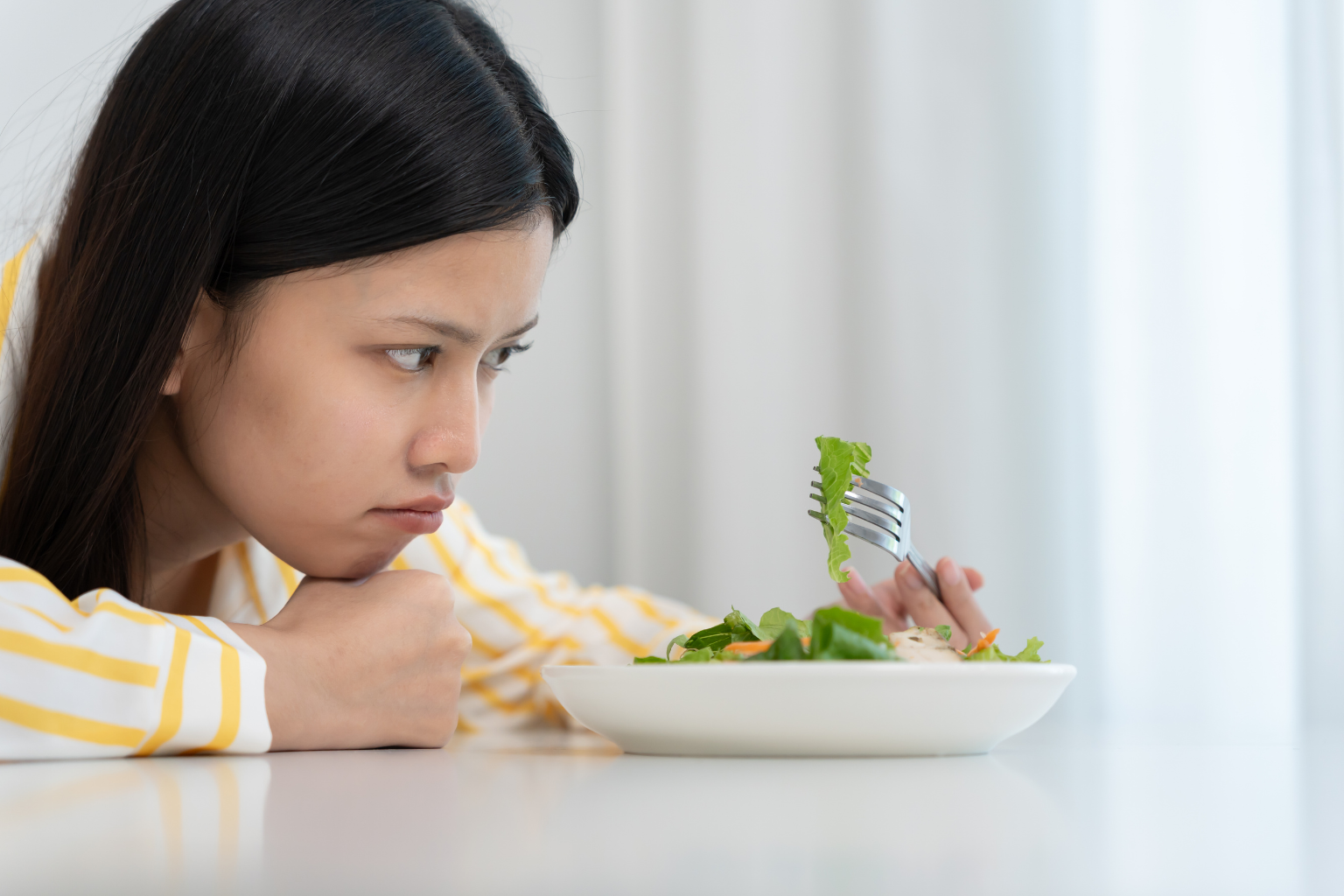 Une femme triste qui mange une salade verte