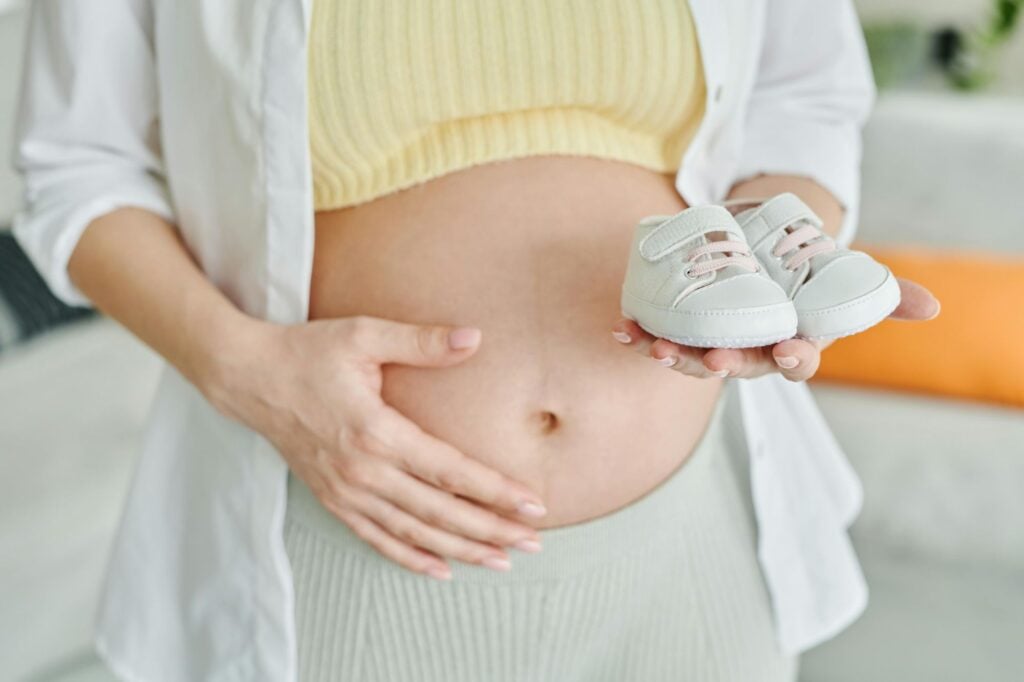 femme enceinte avec petites chaussures de son bébé