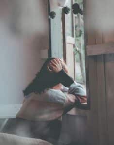 femme de dos regardant par la fenêtre un jardin