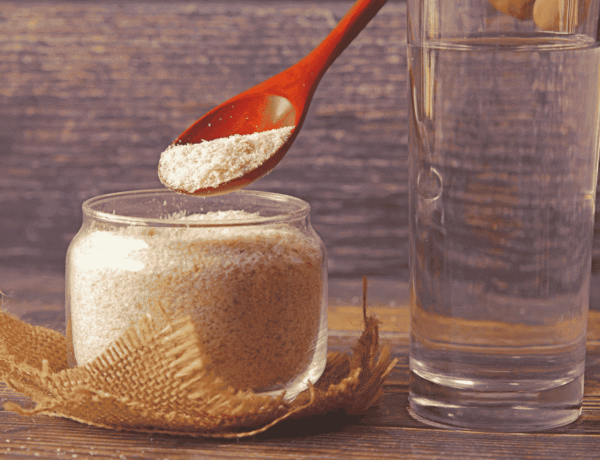 poudre de psyllium blond à côté d'un grand verre d'eau