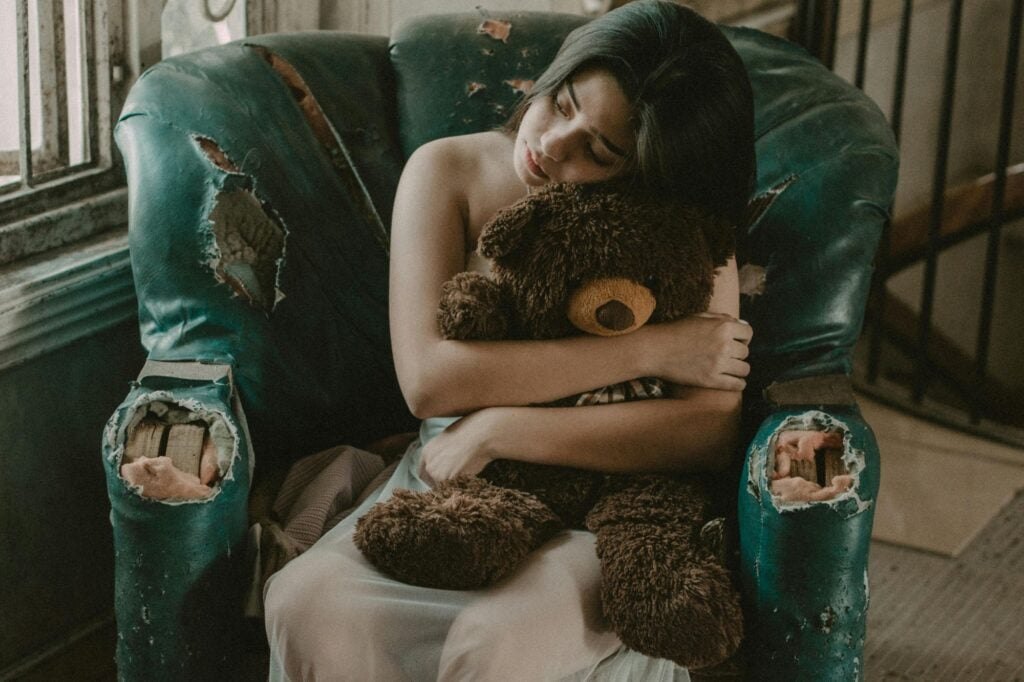 fille seule serrant dans ses bras un nounours