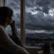 Une personne anxieuse qui regarde un ciel d'orage depuis sa fenêtre